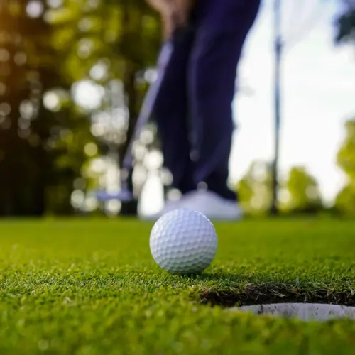 Blurred golfer playing golf in the evening golf course, on sun set evening time.